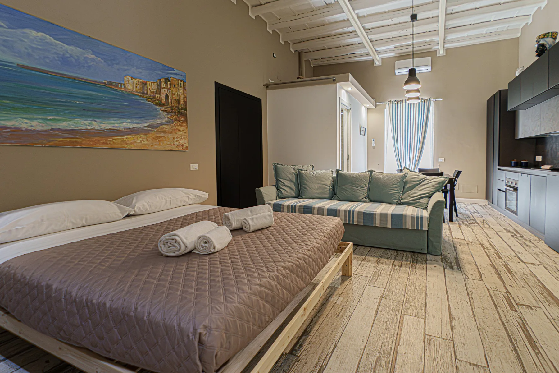 A bedroom and sitting area with a bed and a green sofa.
