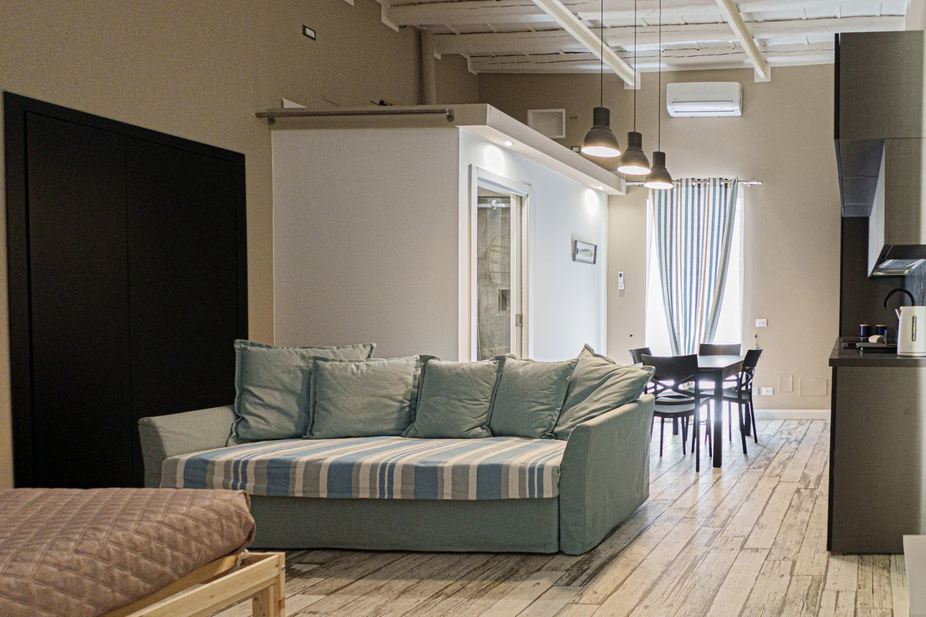 A living and dining area with a green seating area and a table by the window.