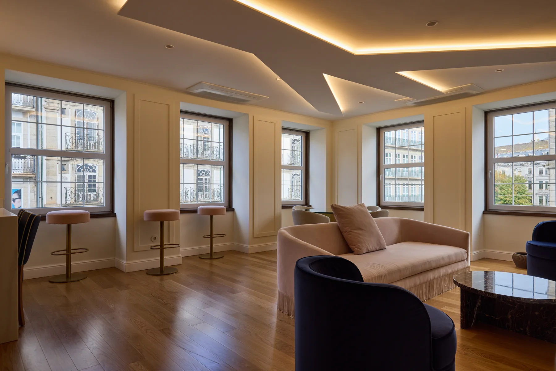 A bright living room with seating, a coffee table, and several large windows.