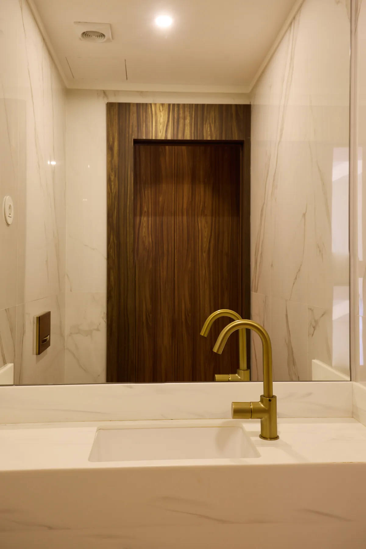 A bathroom vanity with a wide mirror and gold-toned faucet.