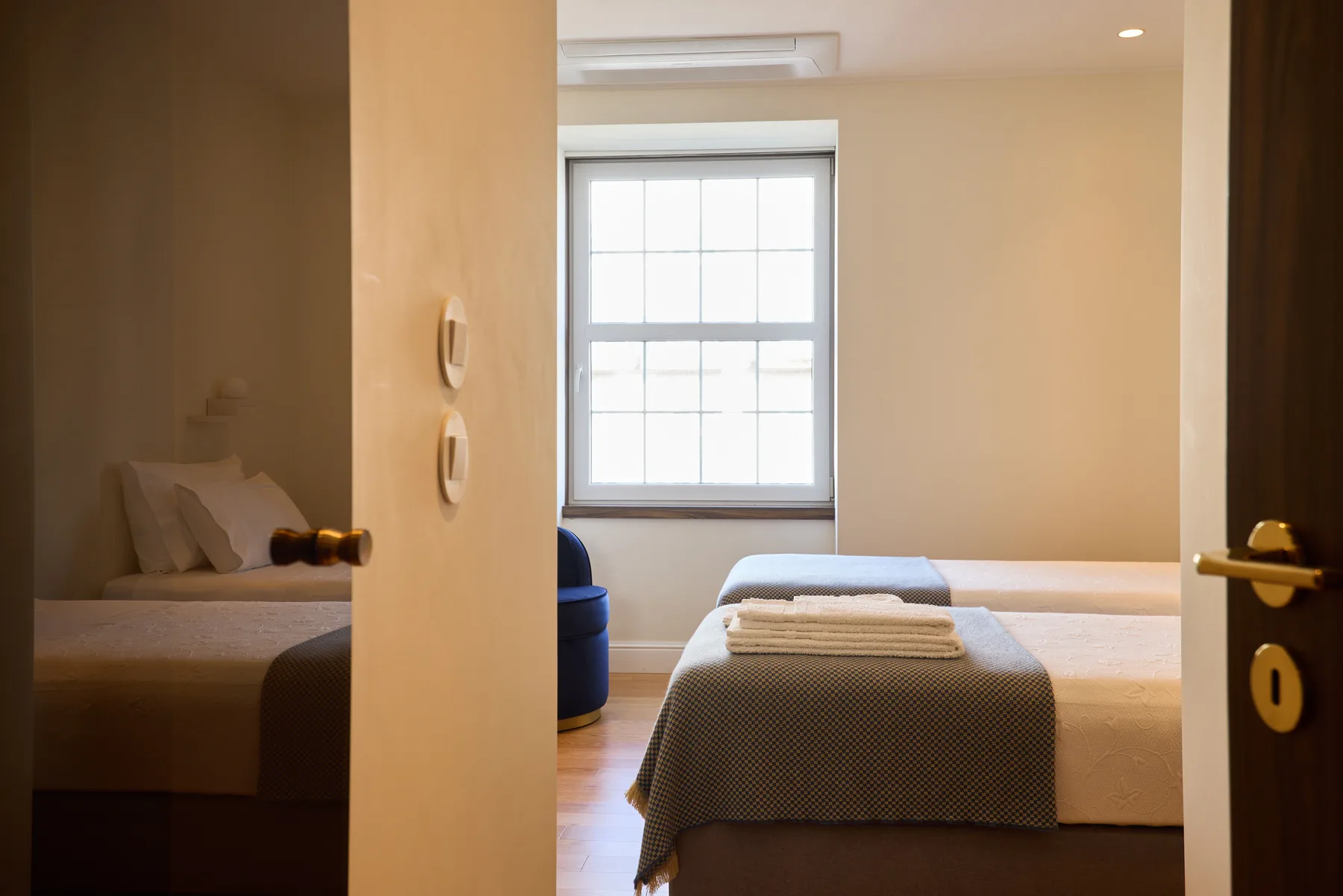 A bedroom with a bed, folded towels, and a large window.