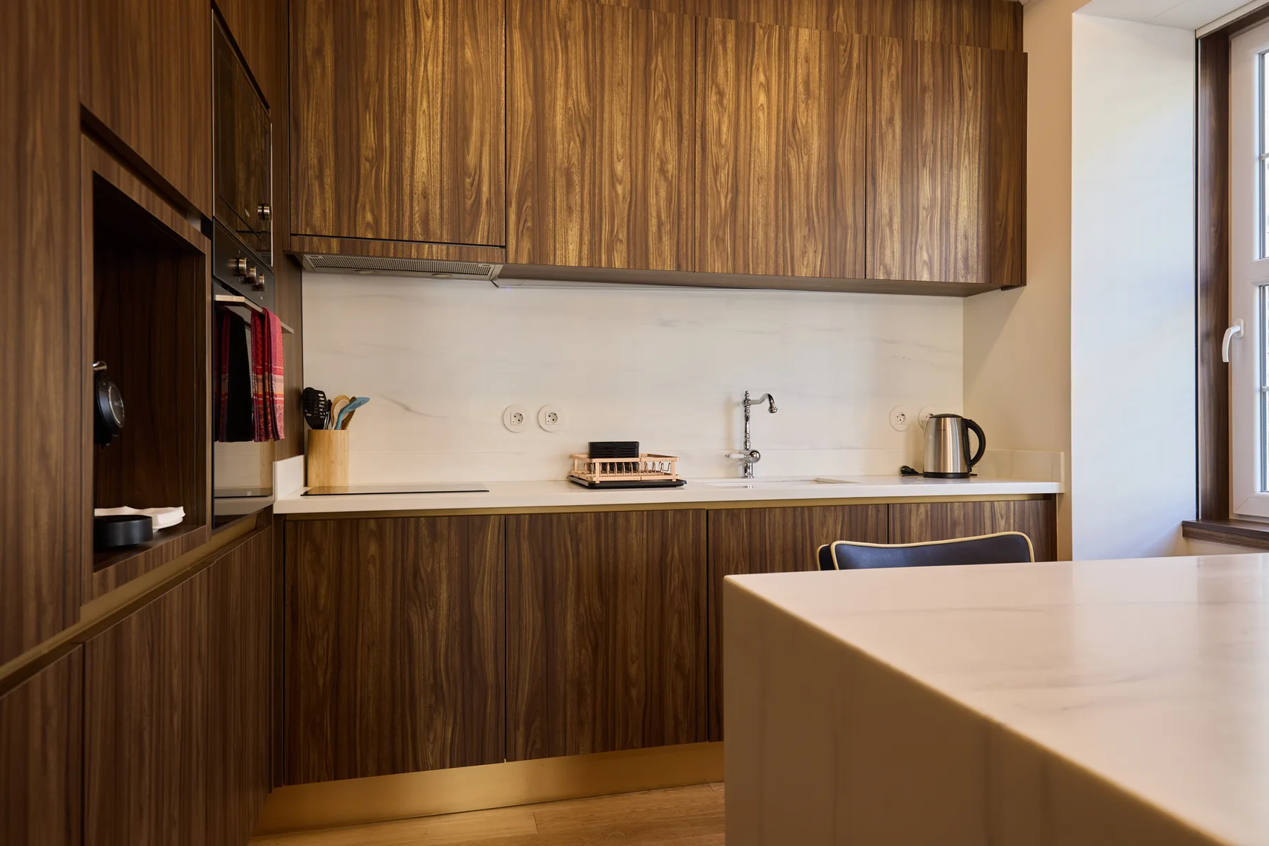 A modern kitchen with dark wood cabinetry and a light countertop.