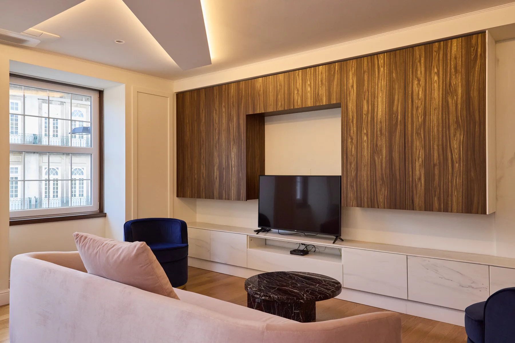A living room with a television set into a wood-paneled wall.