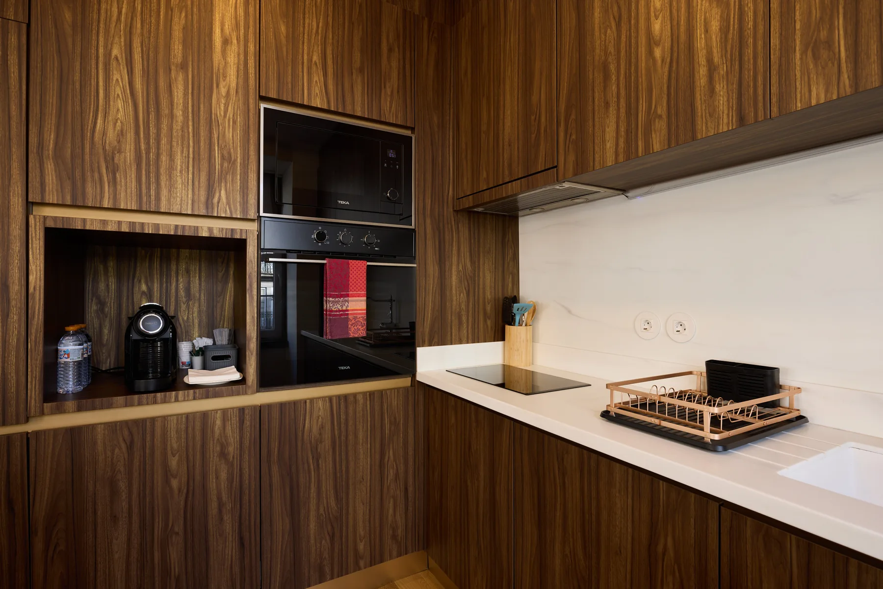 A modern kitchen with dark wood cabinets, built-in appliances, and a white countertop.