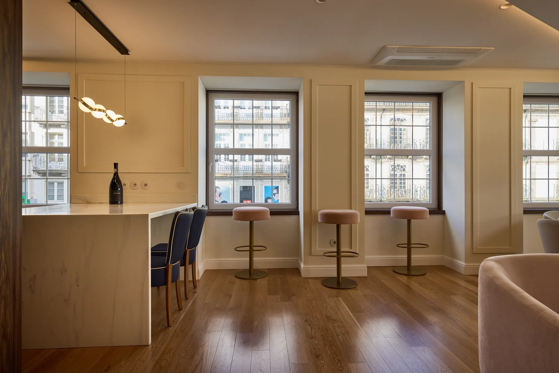 A bright kitchen and dining area with a counter, stools, and large windows.