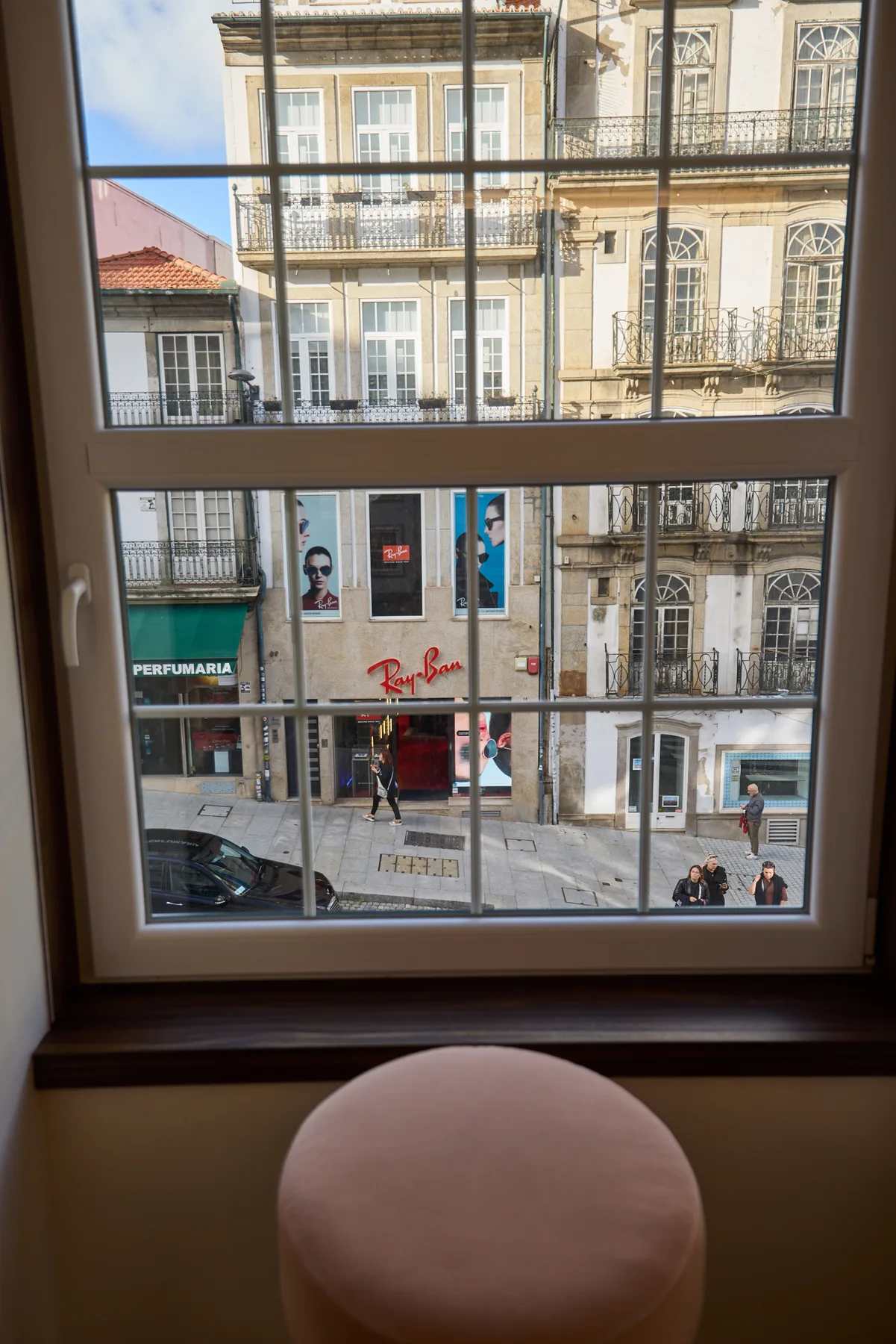 A window overlooks a city street lined with historic-looking buildings.