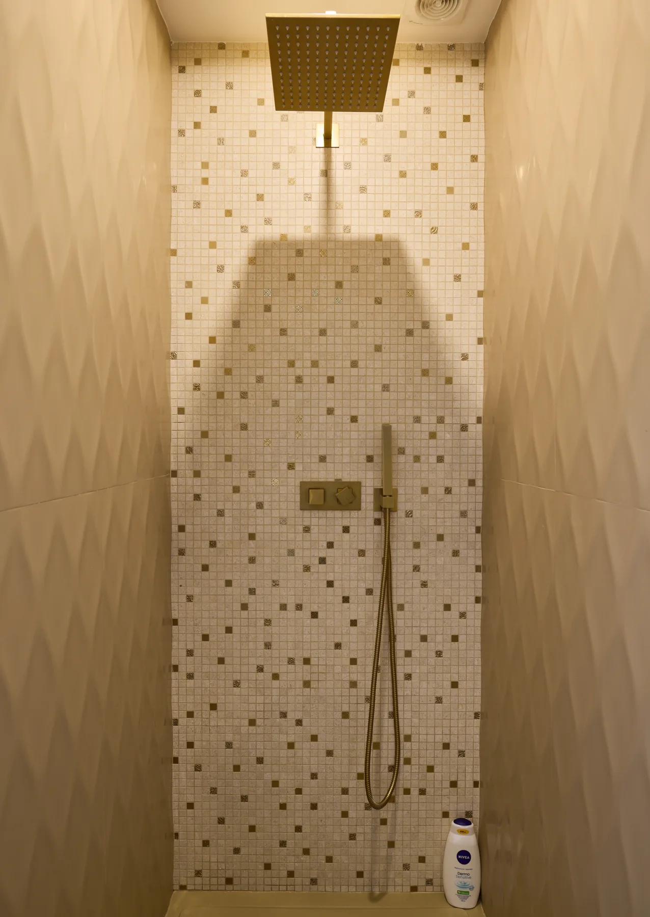 A tiled shower area with a handheld showerhead and overhead shower.