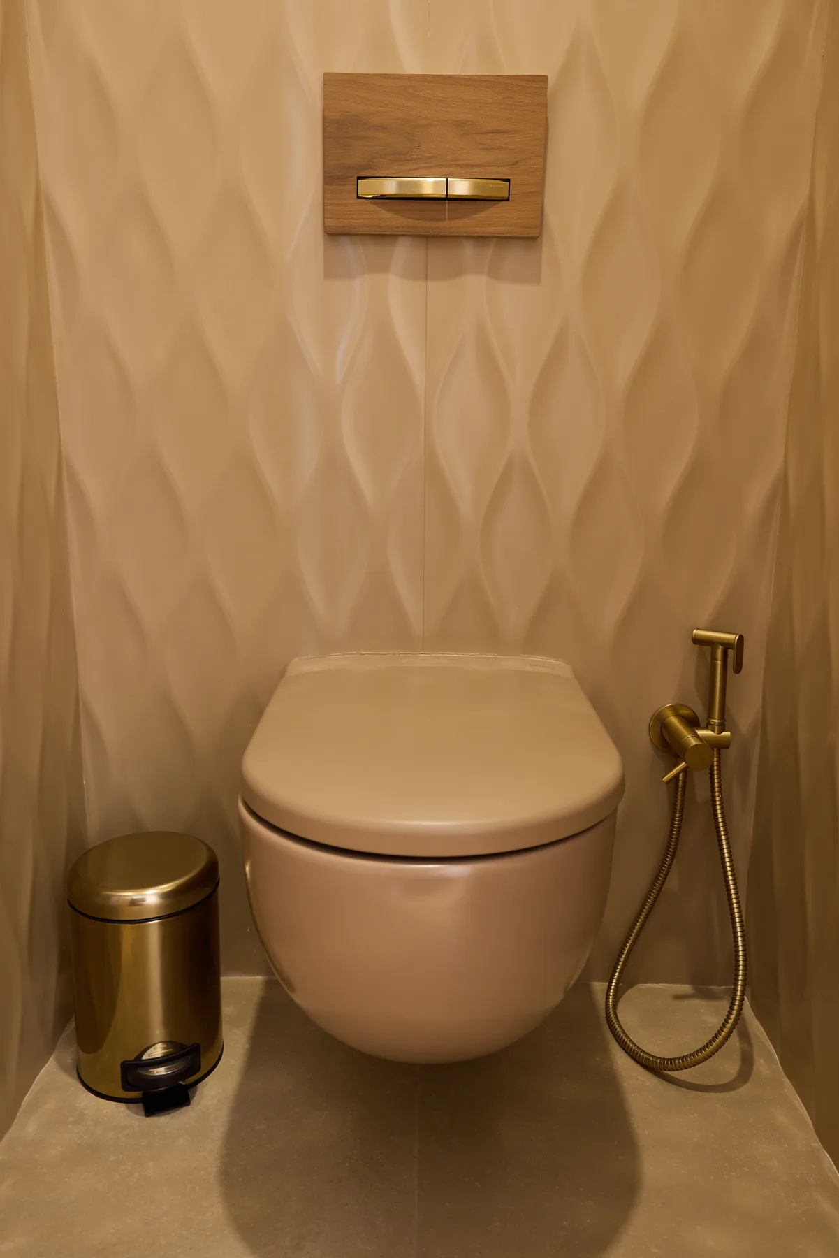 A bathroom with a wall-mounted toilet and a handheld bidet sprayer.