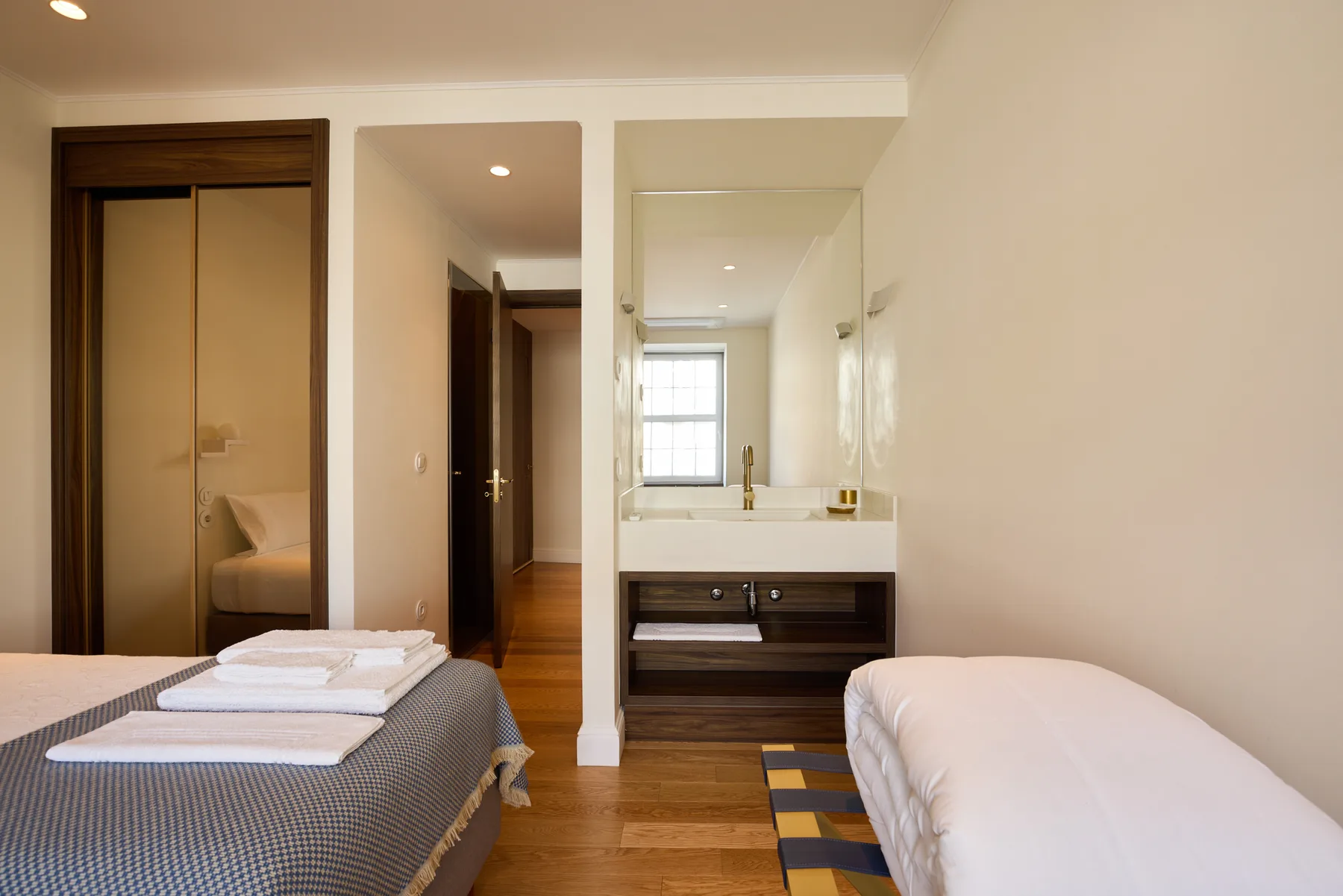 A bedroom with two beds and a washbasin vanity along the back wall.