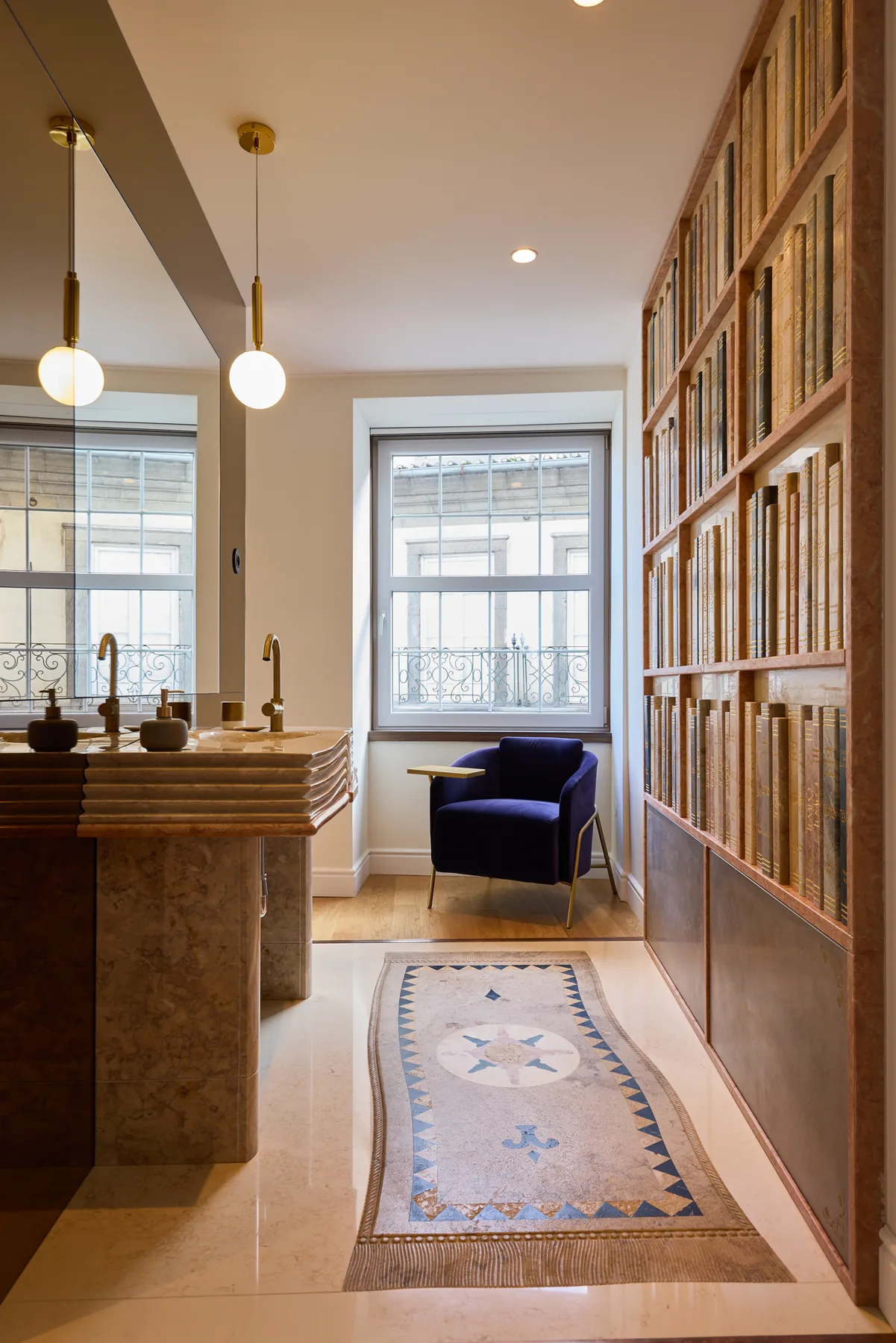 A bright interior with a long wooden bookcase and a small seating area by the window.