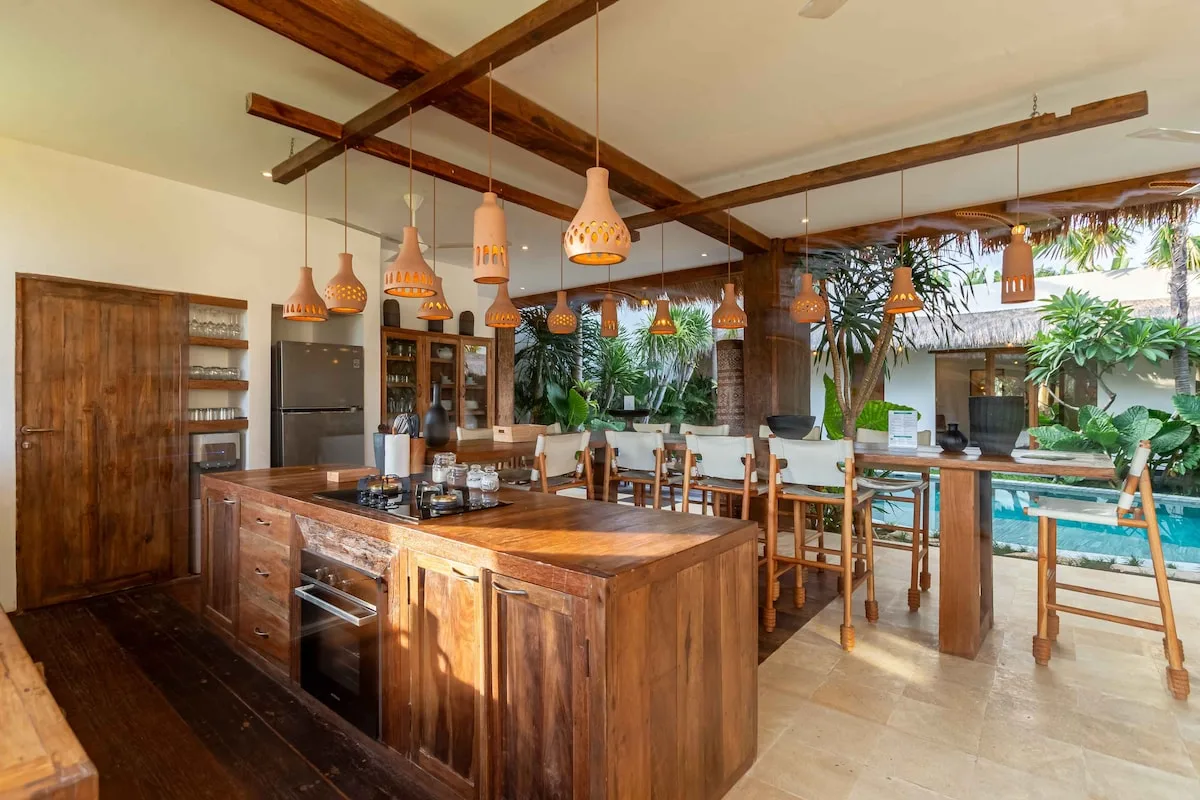 A spacious kitchen with a wooden island and dining table.