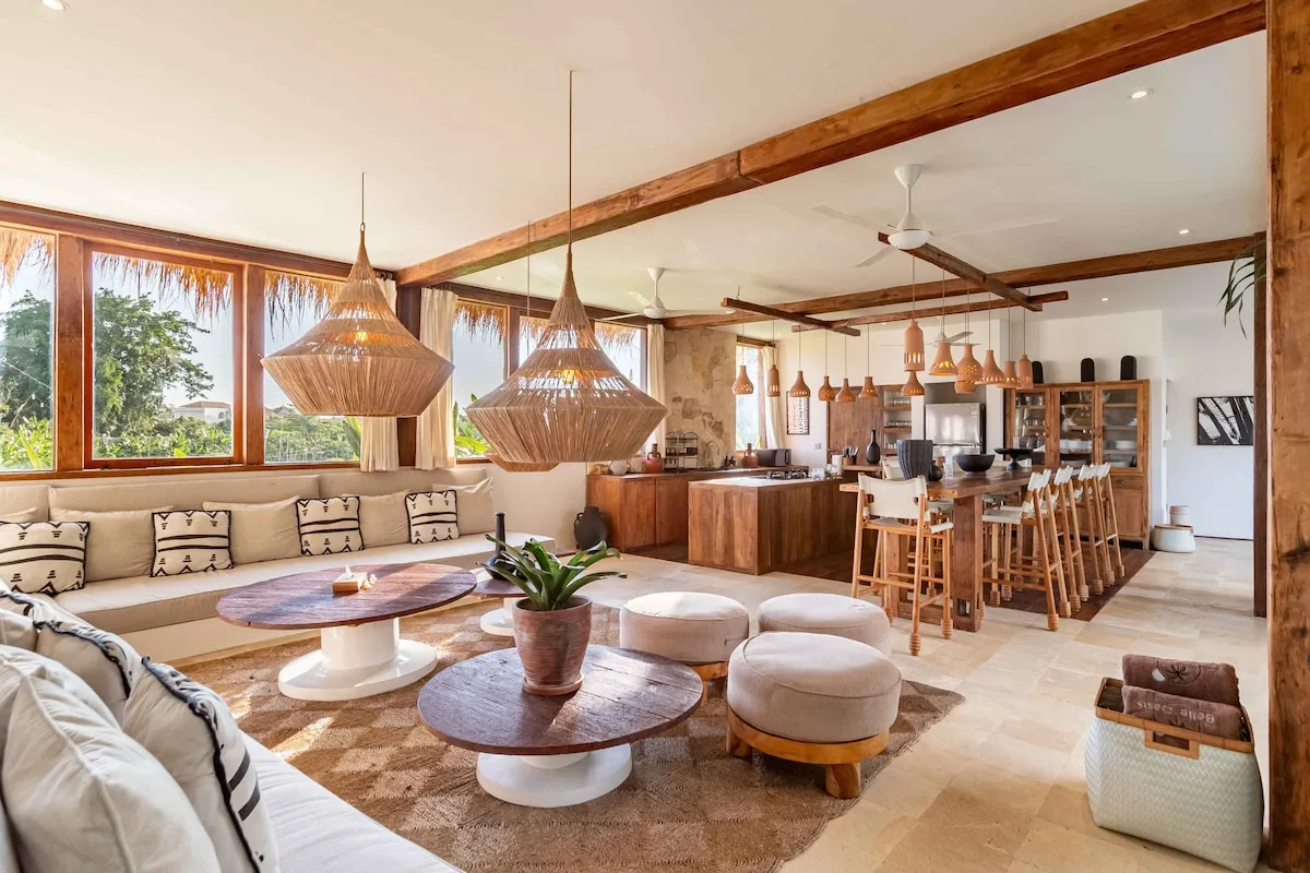 Open-plan living and dining area with wood furnishings and large windows.