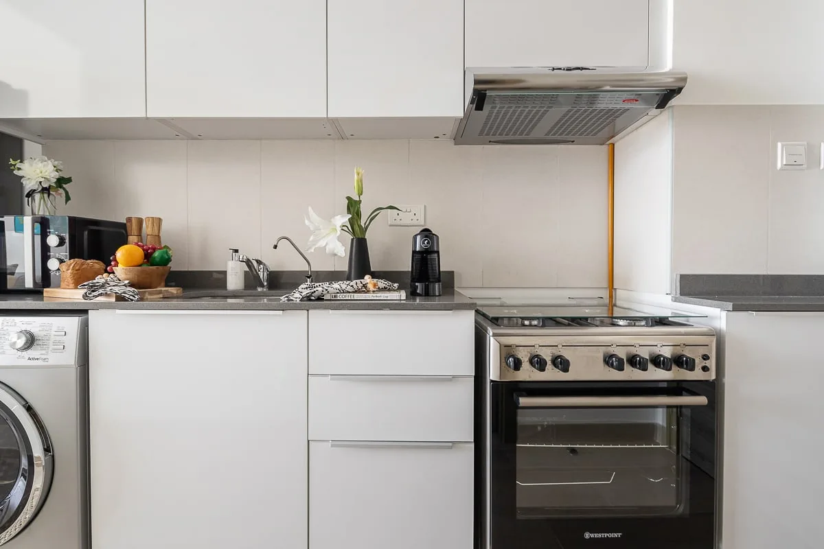 A bright kitchen with white cabinets, a countertop, and a freestanding stove.