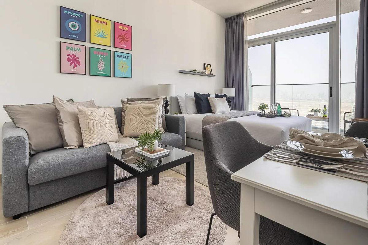 A bright living room has gray seating, a coffee table, and large windows.