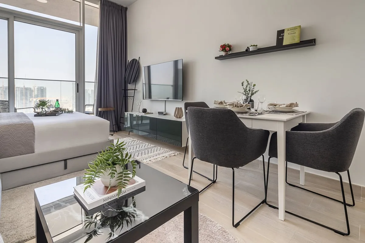 A bright bedroom and dining area with a large window and contemporary furnishings.