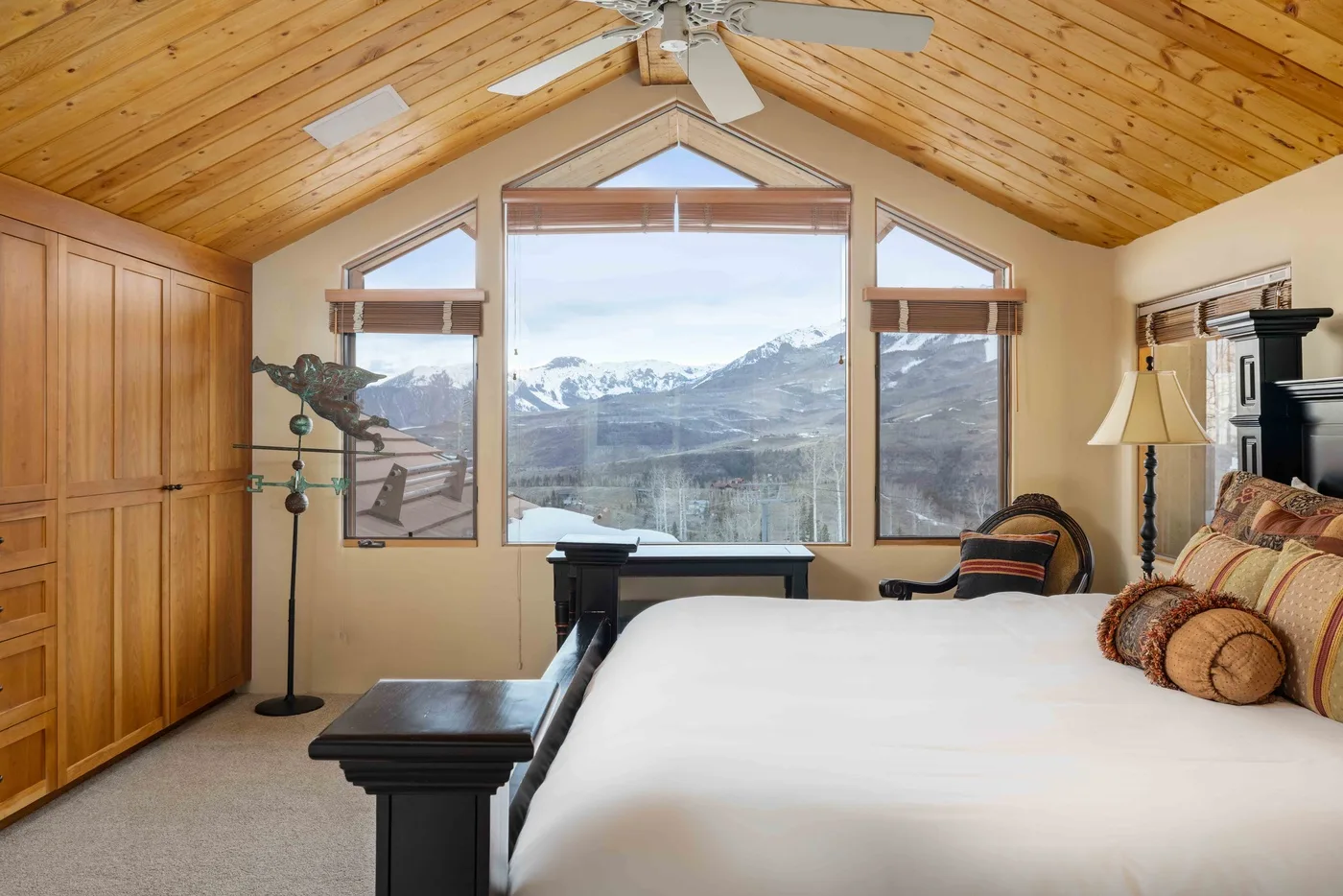 Un dormitorio con una cama grande y vistas a las montañas por las ventanas.