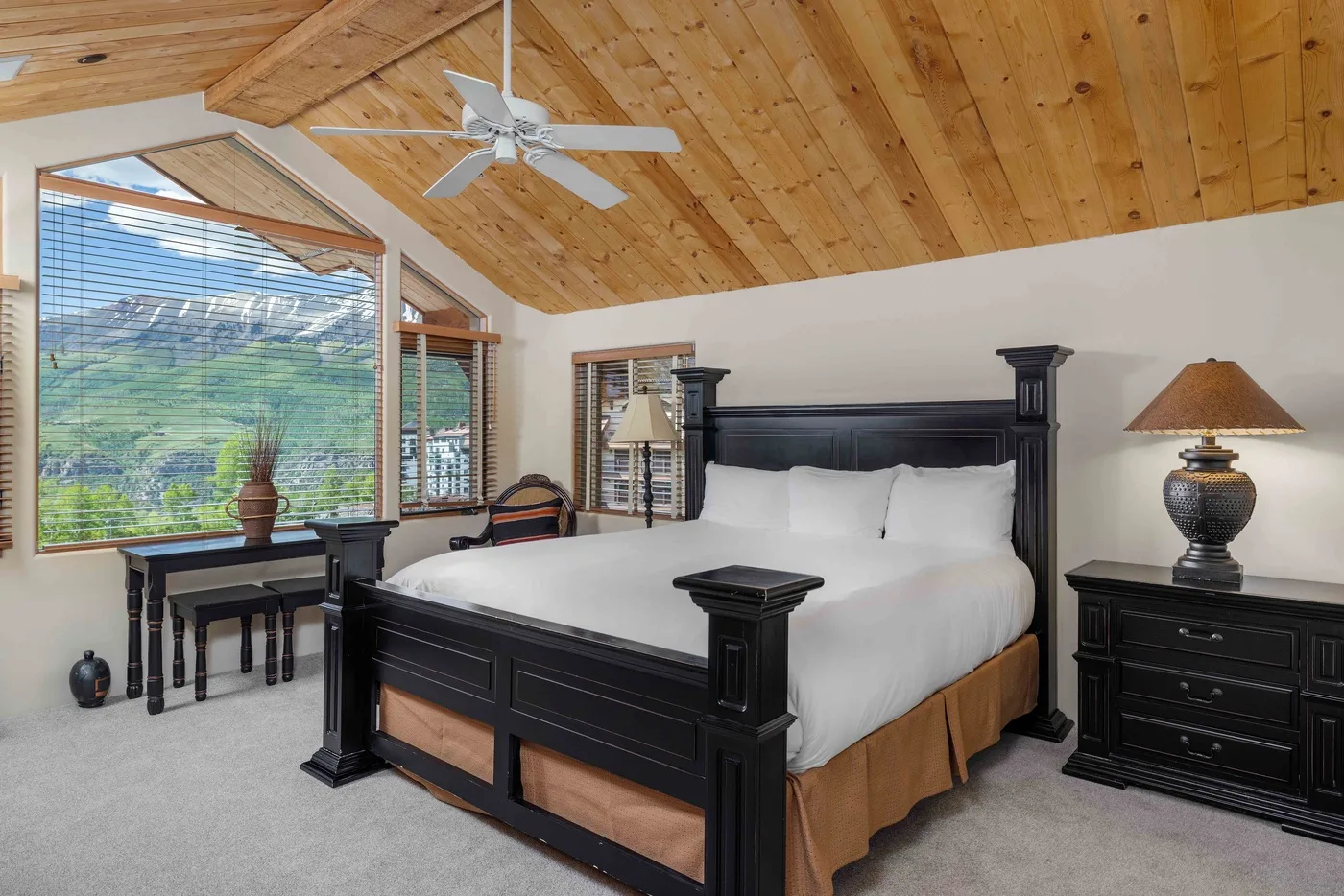 Un dormitorio con una cama grande bajo un techo inclinado revestido de madera.