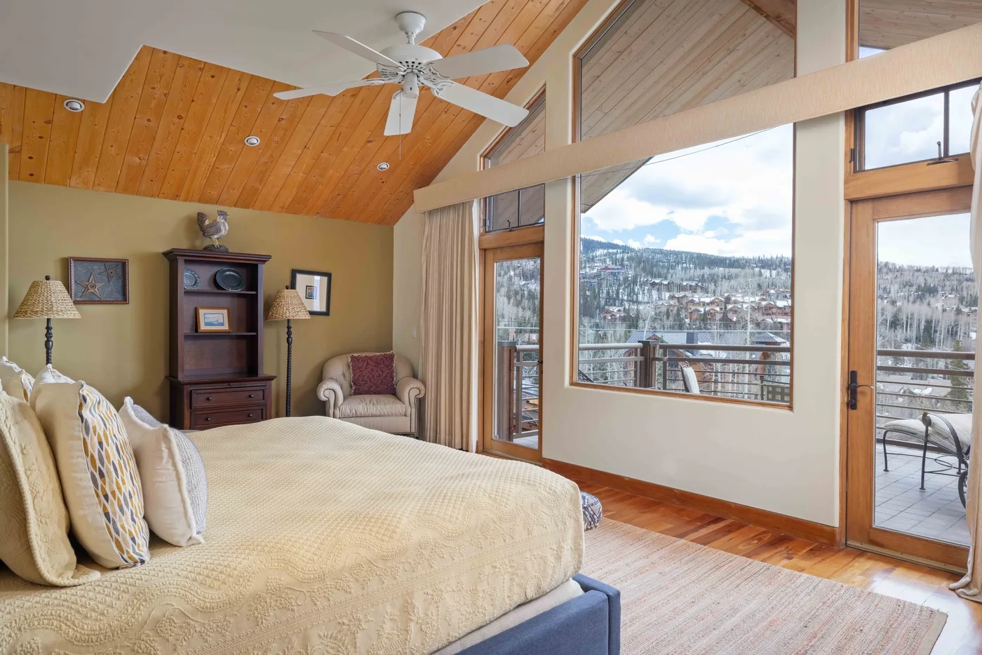 Dormitorio con una cama grande, techo revestido de madera y vistas al balcón.