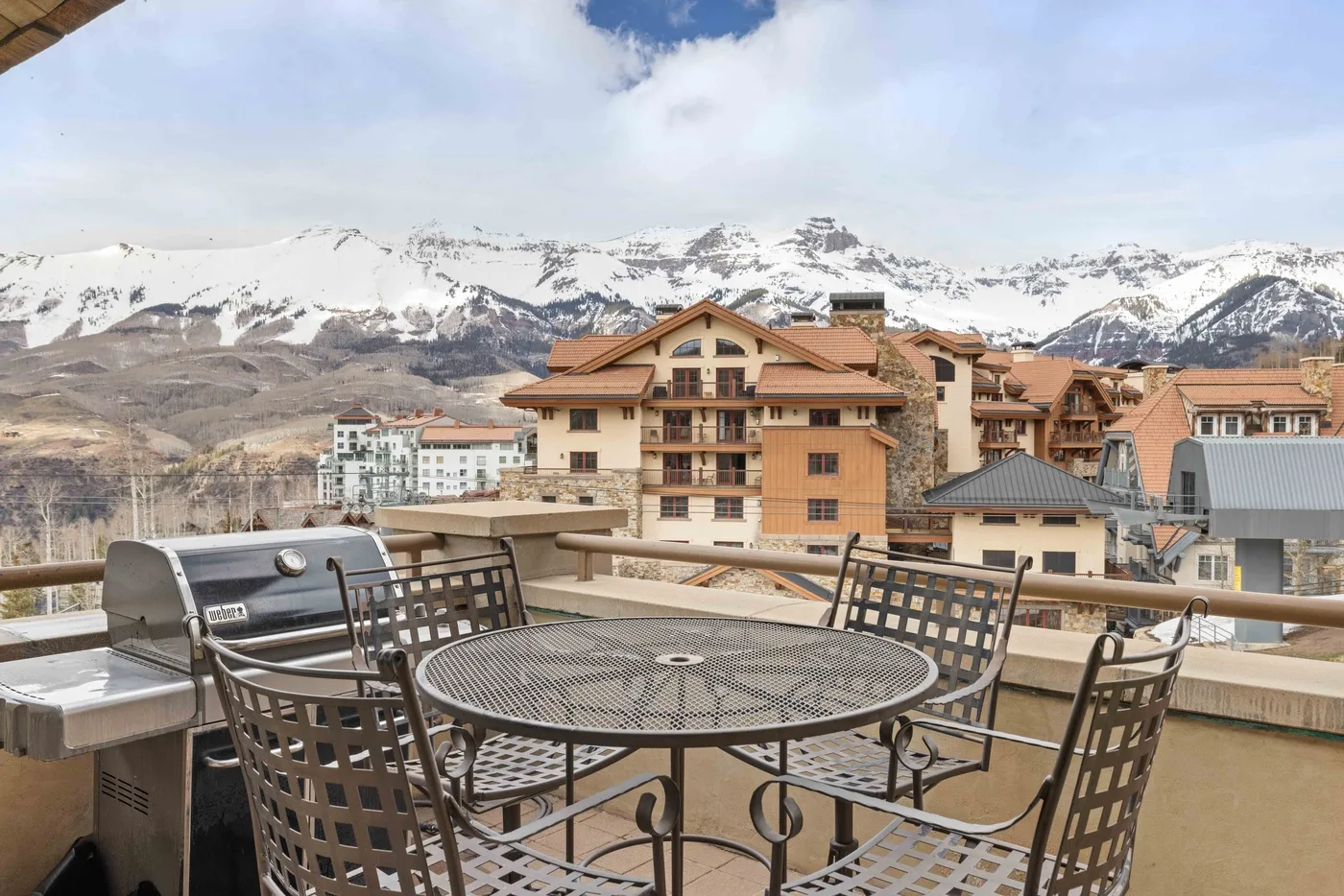Una terraza en la azotea tiene muebles metálicos de comedor con vistas a las montañas.