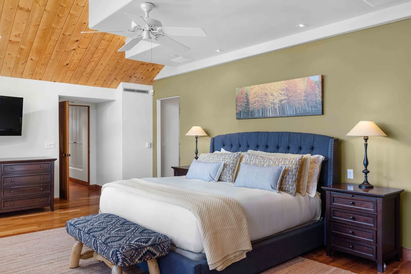 Un dormitorio con una cama grande, mesitas de noche y un techo de madera.