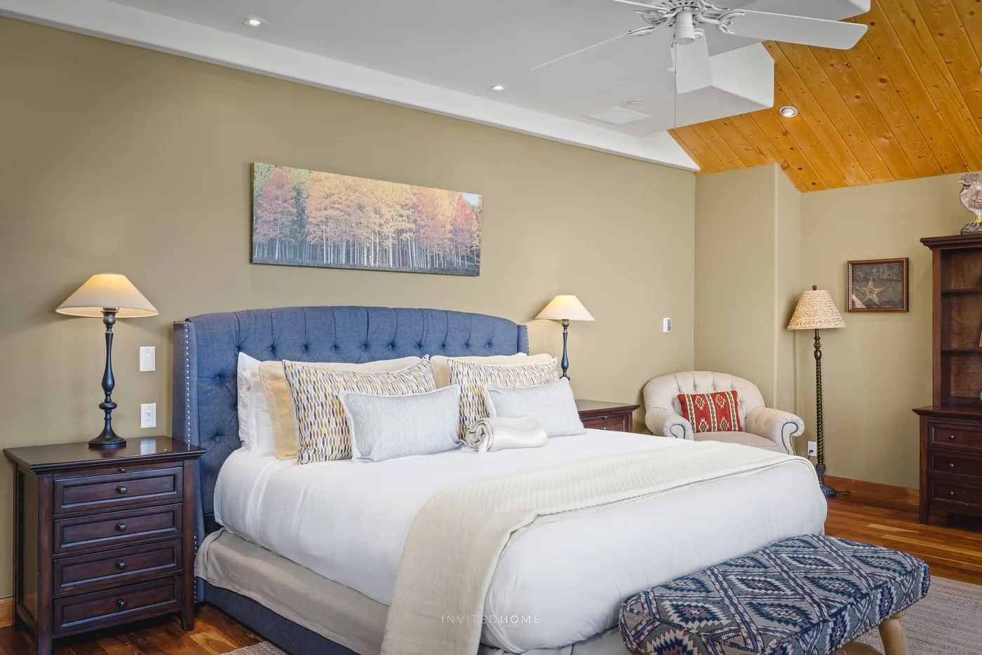 Un dormitorio con una cama grande bajo un cabecero tapizado azul.