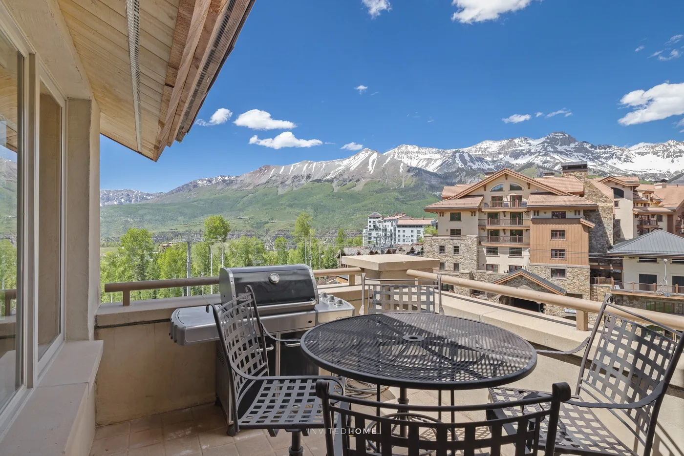 Una terraza amueblada al aire libre ofrece vistas a las montañas y los edificios cercanos.