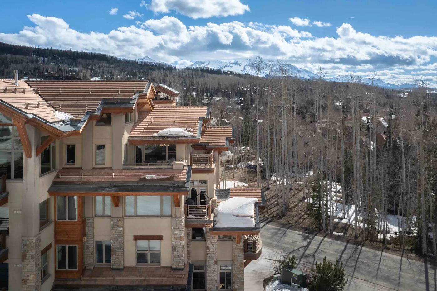 Edificios de montaña se alzan entre árboles sin hojas bajo un cielo nublado.