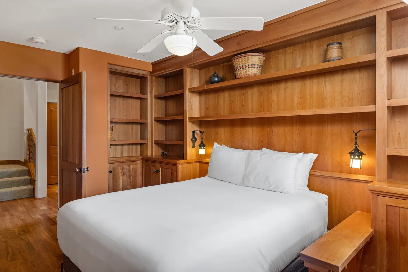 Un dormitorio con una cama blanca frente a una pared de estanterías de madera.