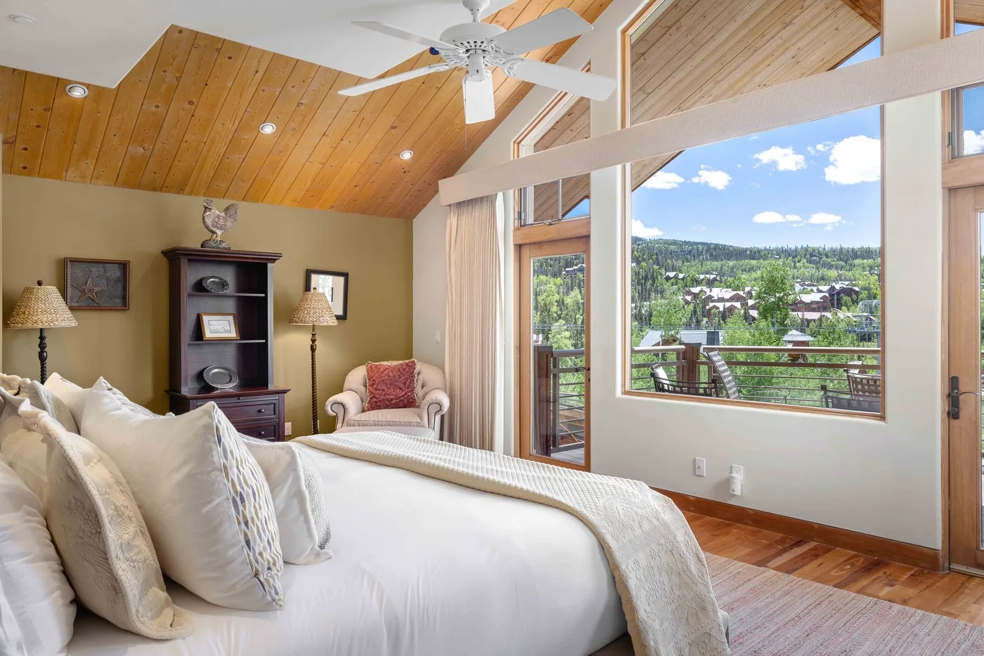 Un dormitorio luminoso con una cama grande y amplias ventanas con vistas a un paisaje verde.