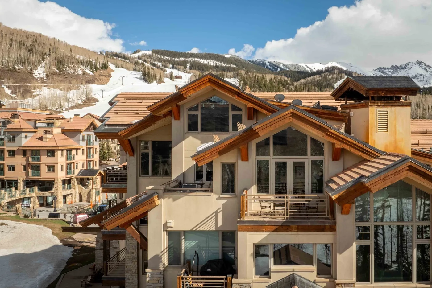 Un edificio de montaña con tejados de madera y laderas nevadas al fondo.