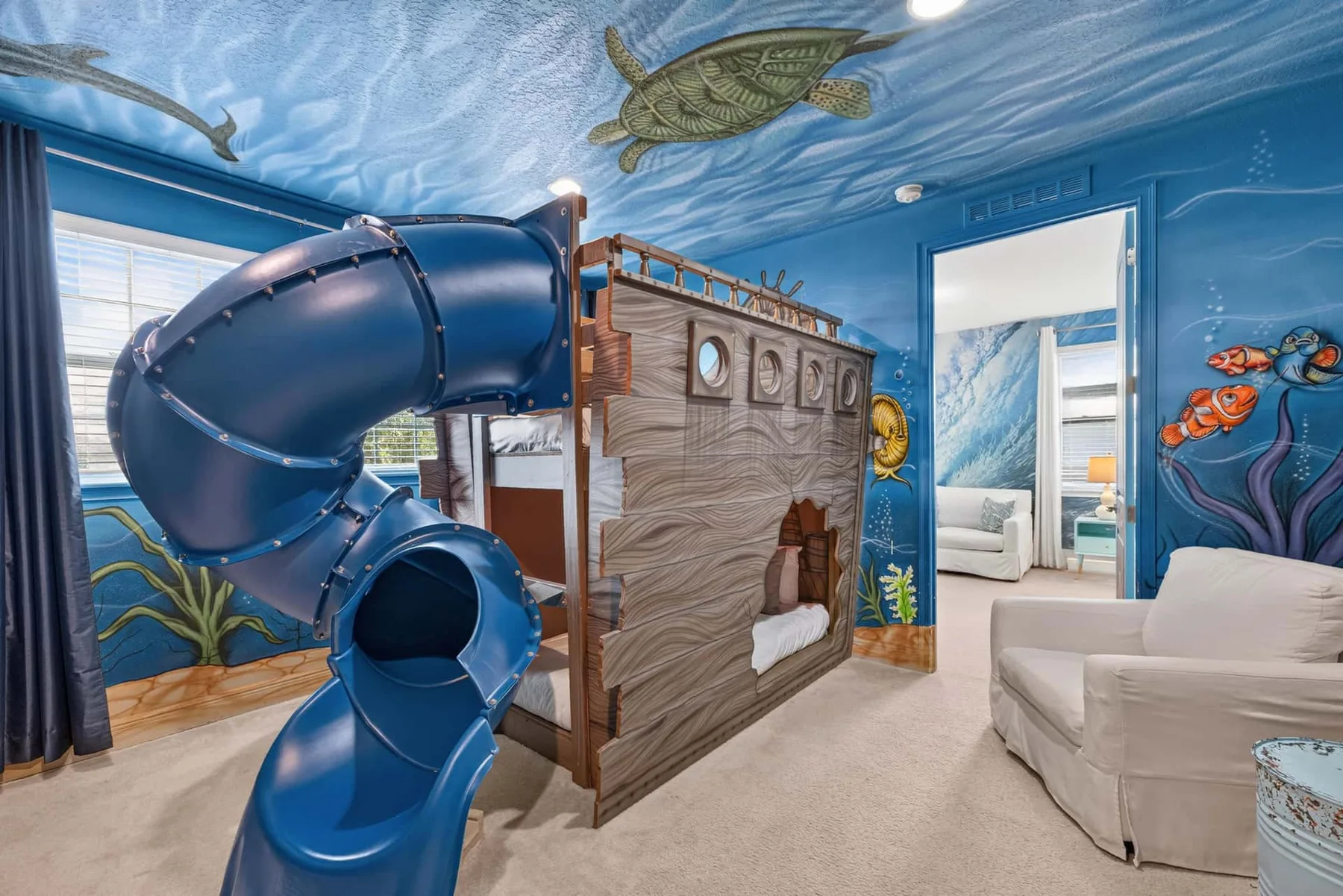 A blue underwater-themed bedroom features a large indoor slide and built-in bunk beds.