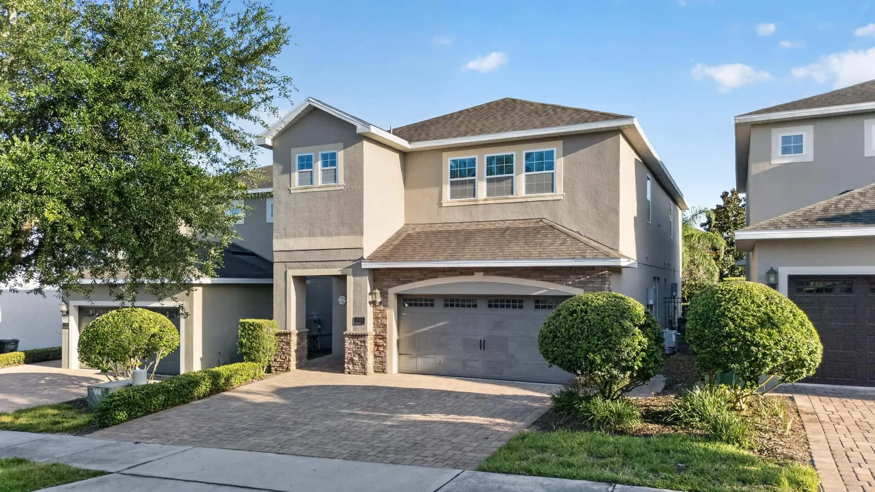 A two-story house with a driveway, garage, and landscaped shrubs.