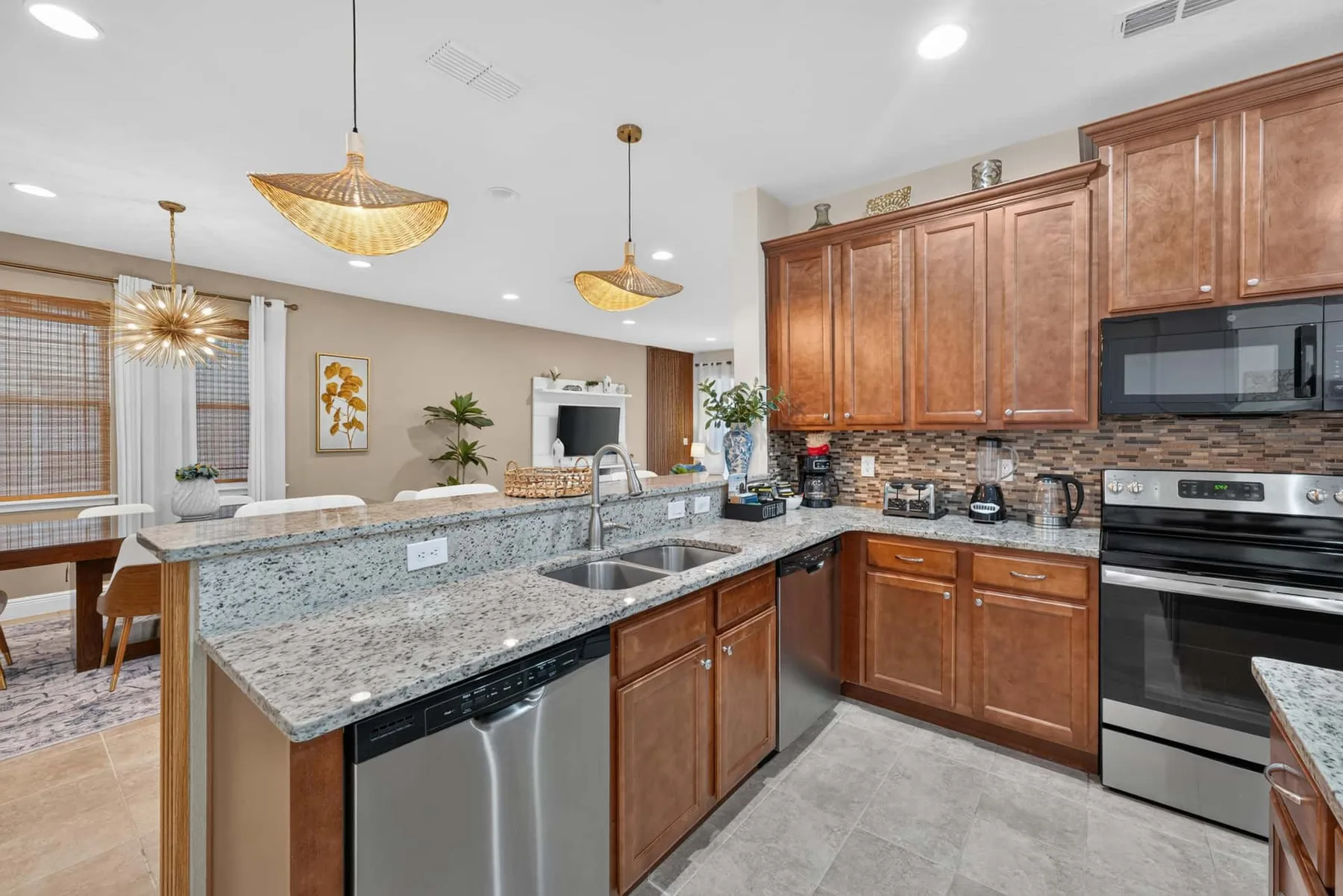 A spacious kitchen with wooden cabinets, stone countertops, and stainless steel appliances.