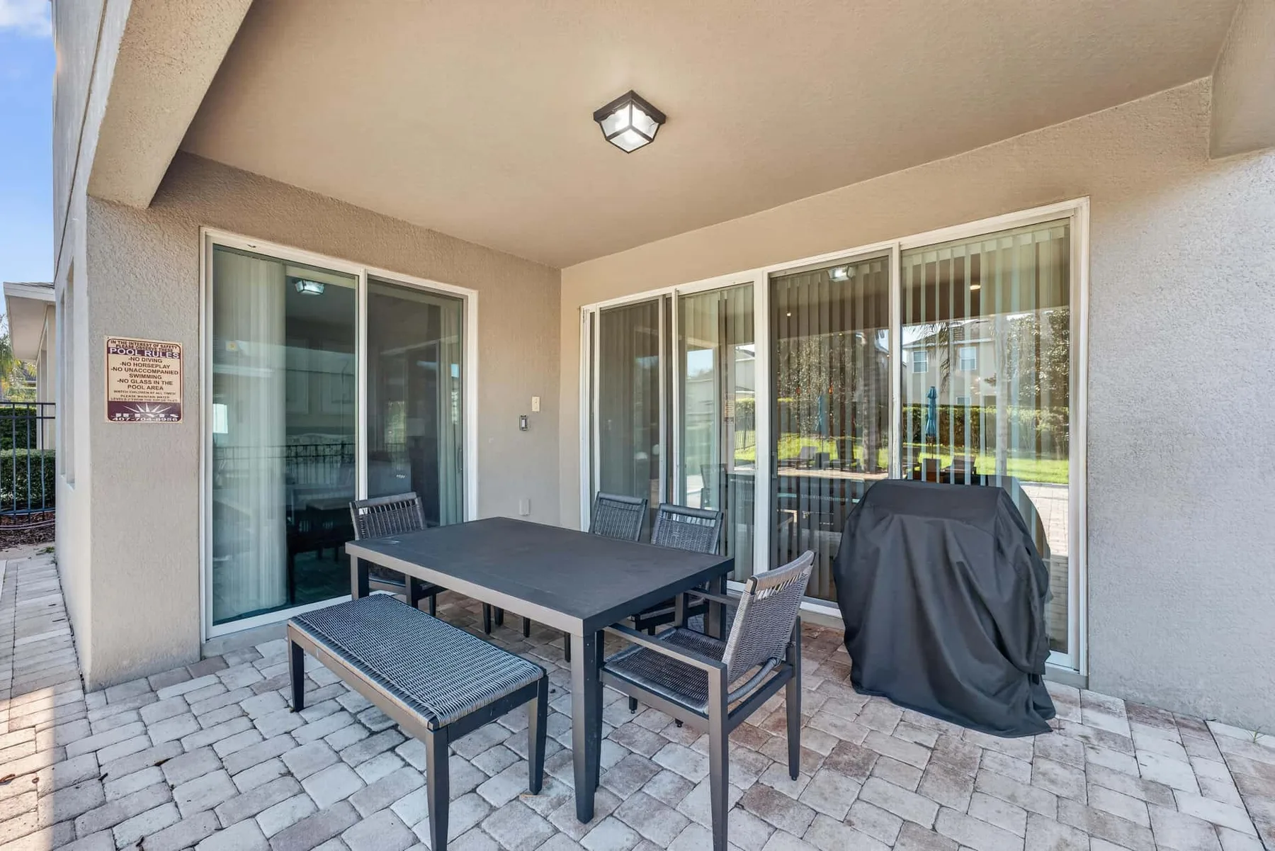 A covered patio with outdoor seating and a table beside large glass doors.
