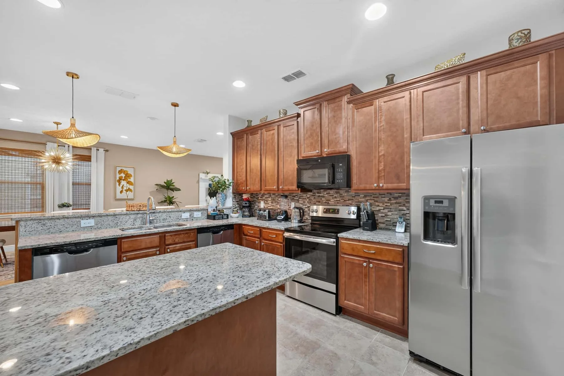 A spacious kitchen with wooden cabinets, granite counters, and stainless steel appliances.