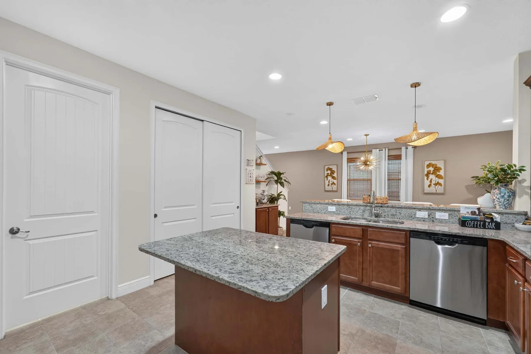 A bright kitchen with a granite island and wooden cabinetry.