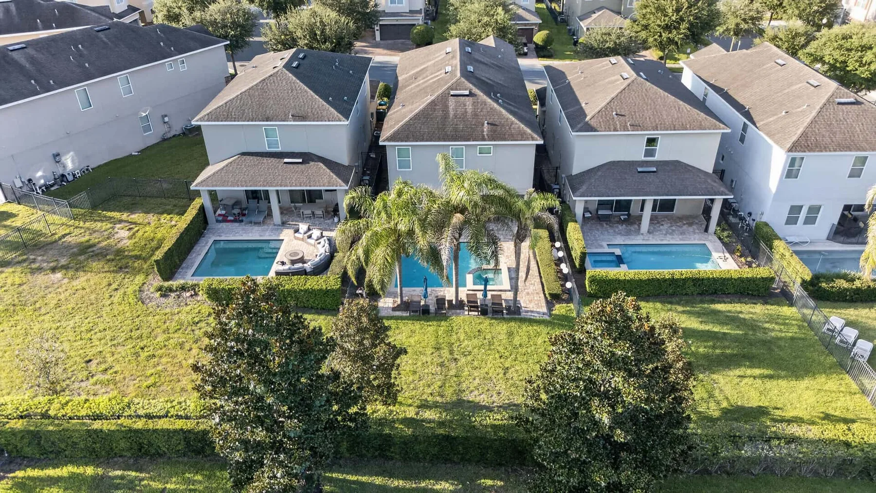 An aerial view of neighboring homes with backyards, pools, and lawns.