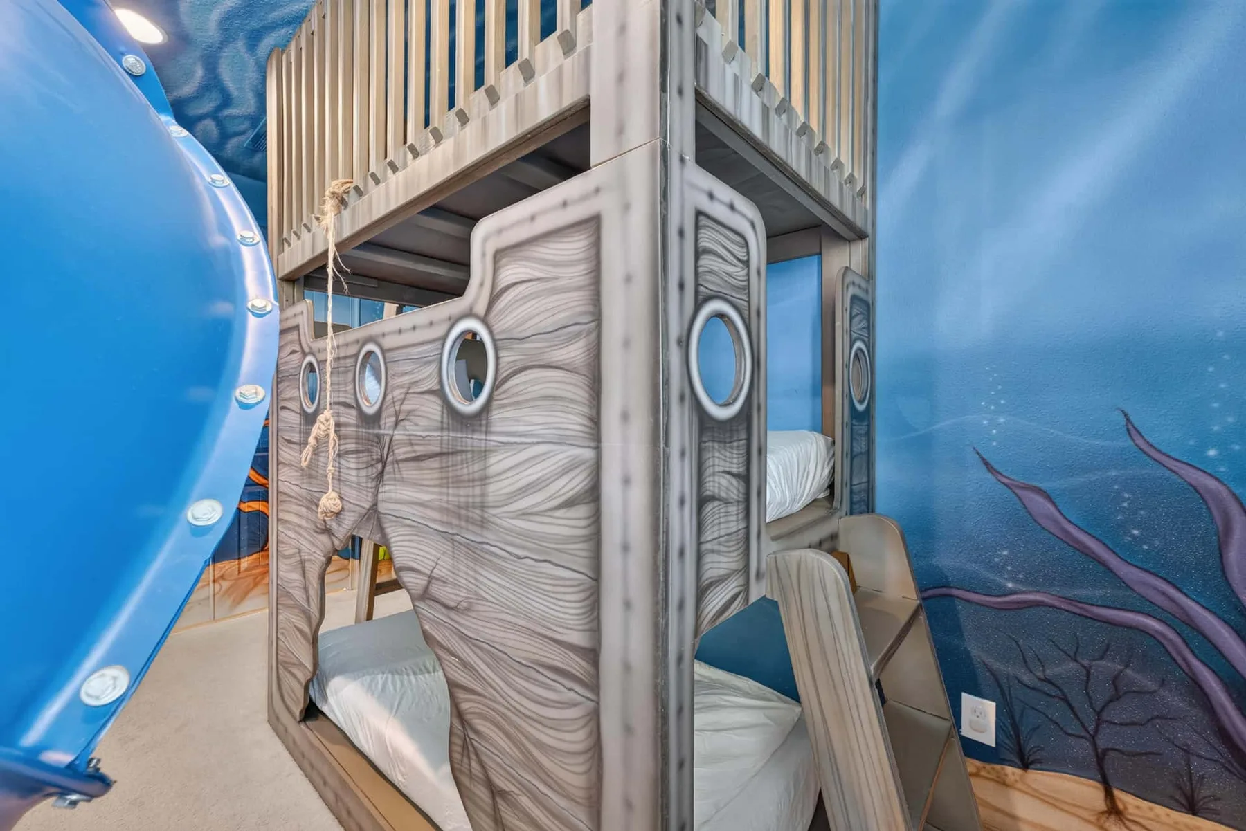 A themed bunk-bed room has wood-patterned bed frames and blue underwater wall art.