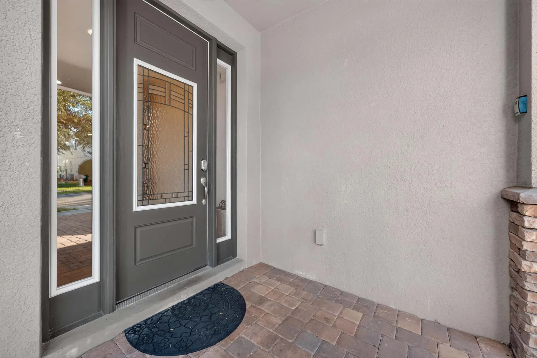 A covered entryway with a dark front door and a tiled floor.