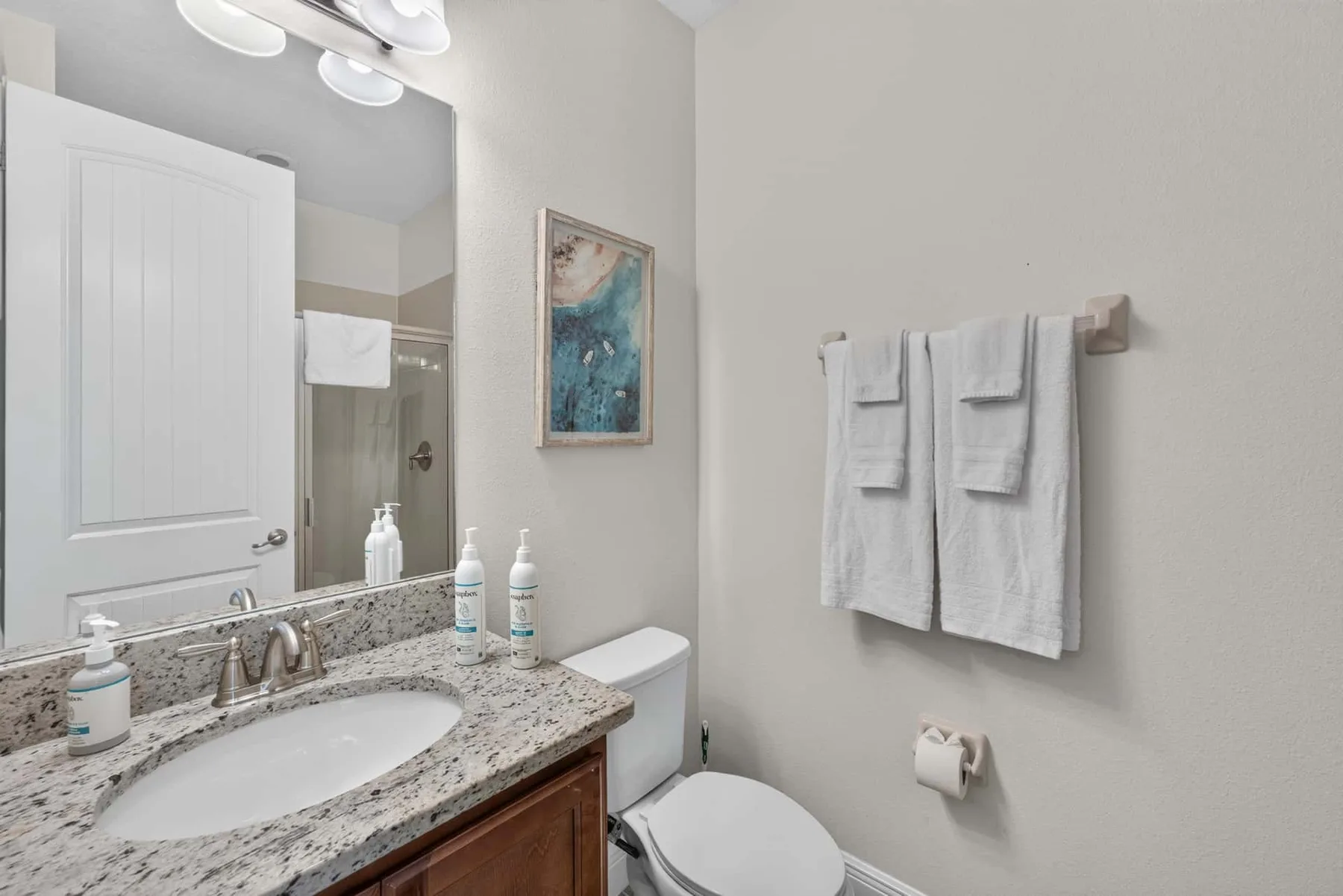 A bathroom with a sink, toilet, and towels hanging on the wall.