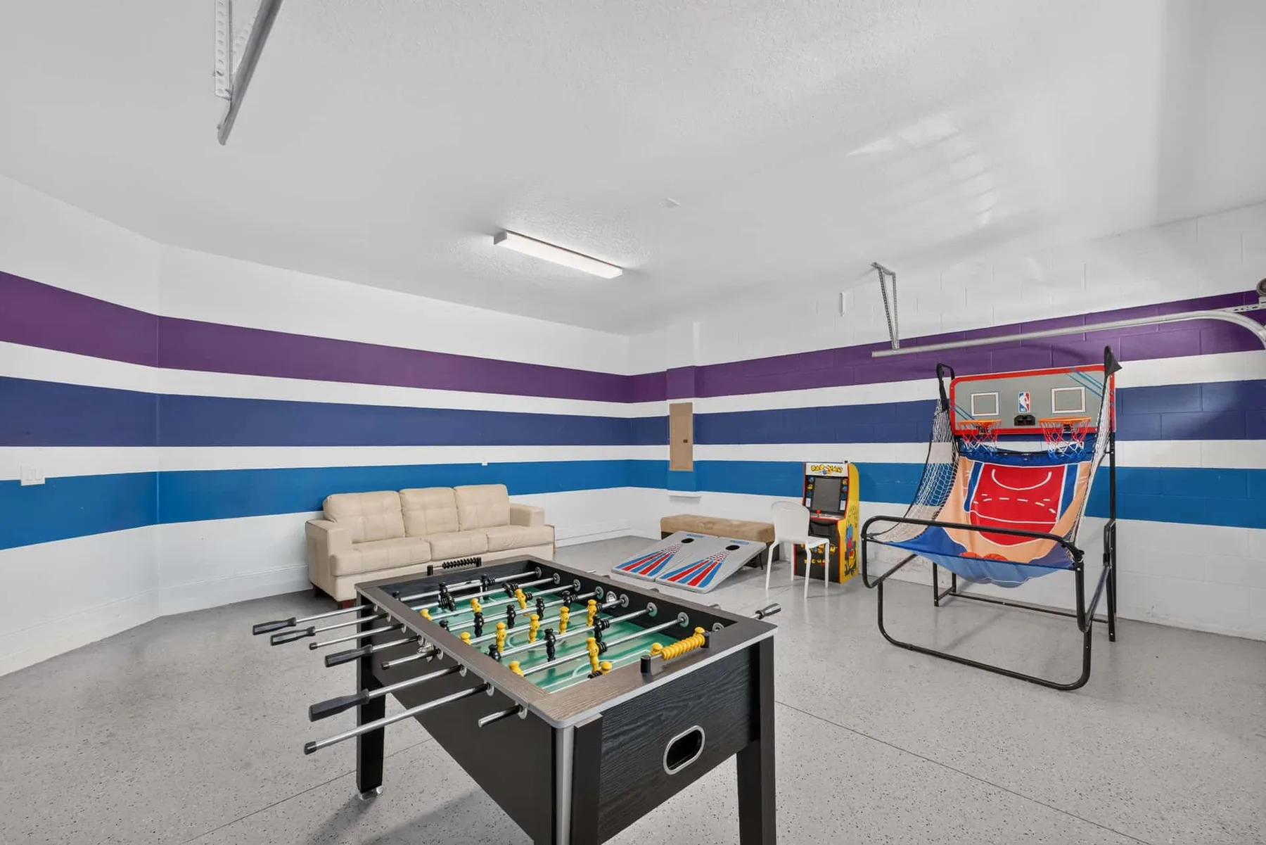 A game room with a foosball table and an arcade basketball game.