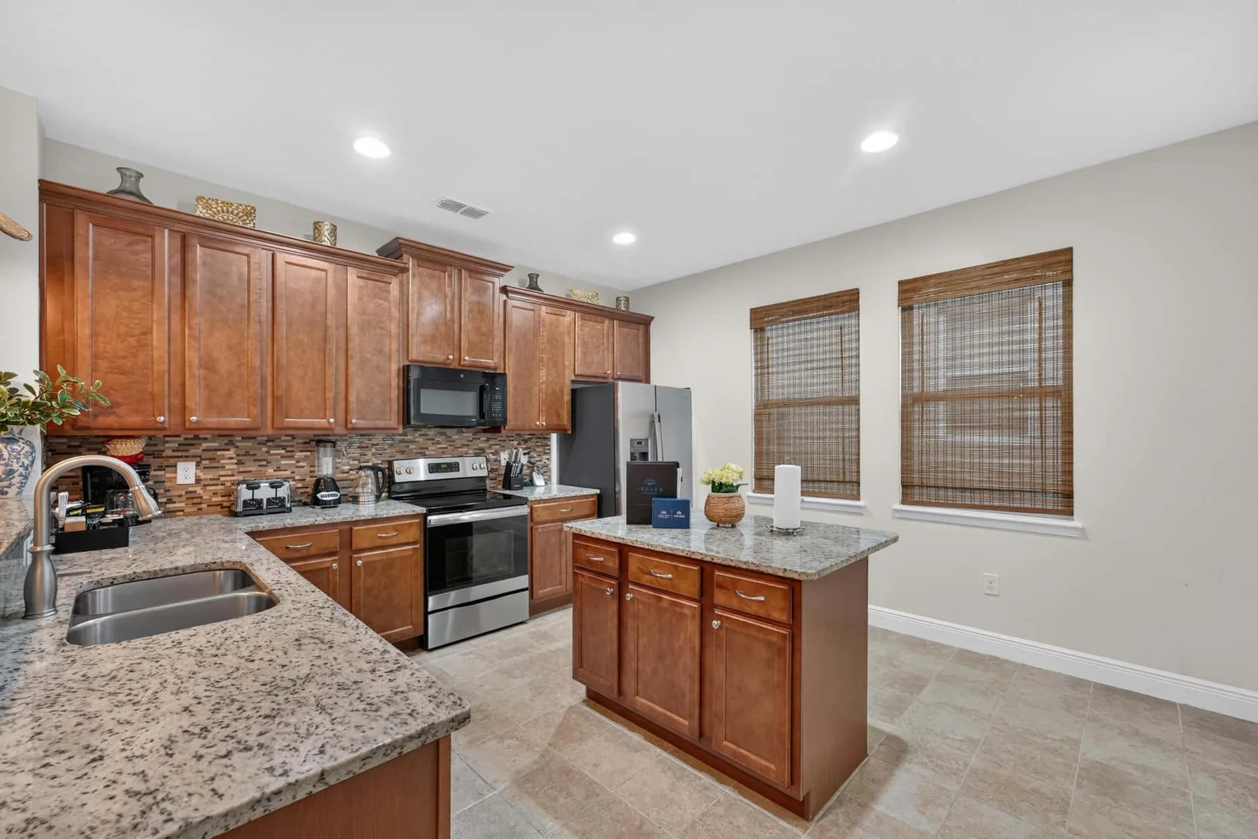 A kitchen with wooden cabinets, granite countertops, and a central island.