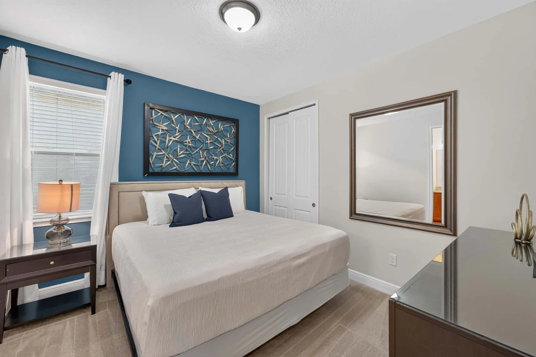 A bedroom with a bed, a blue accent wall, and a bedside table.