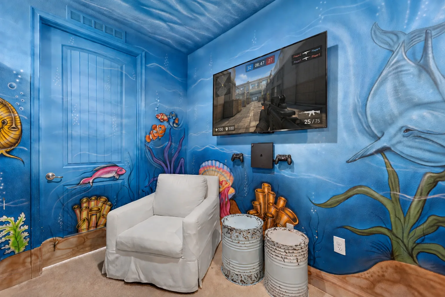 A blue underwater-themed room with a white armchair and a wall-mounted screen.