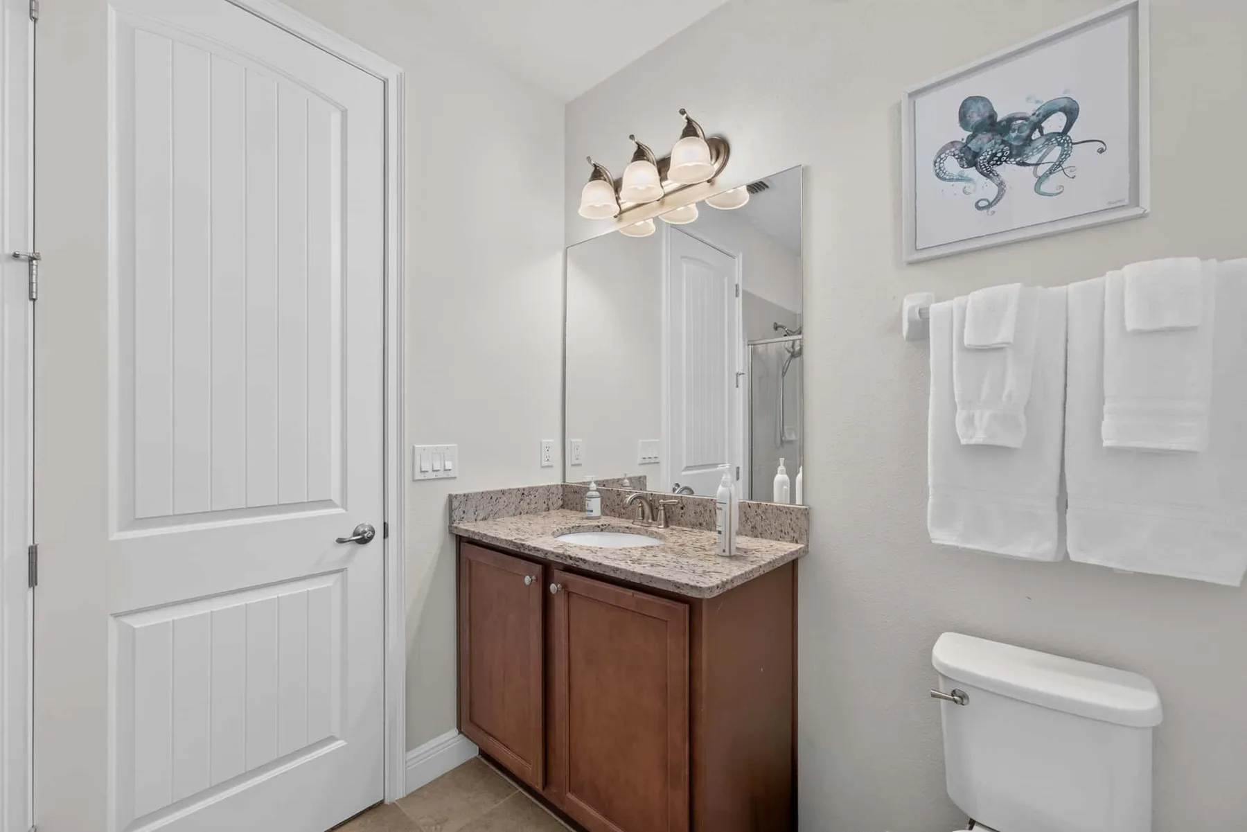A bathroom vanity with a mirror, towels, and a toilet.