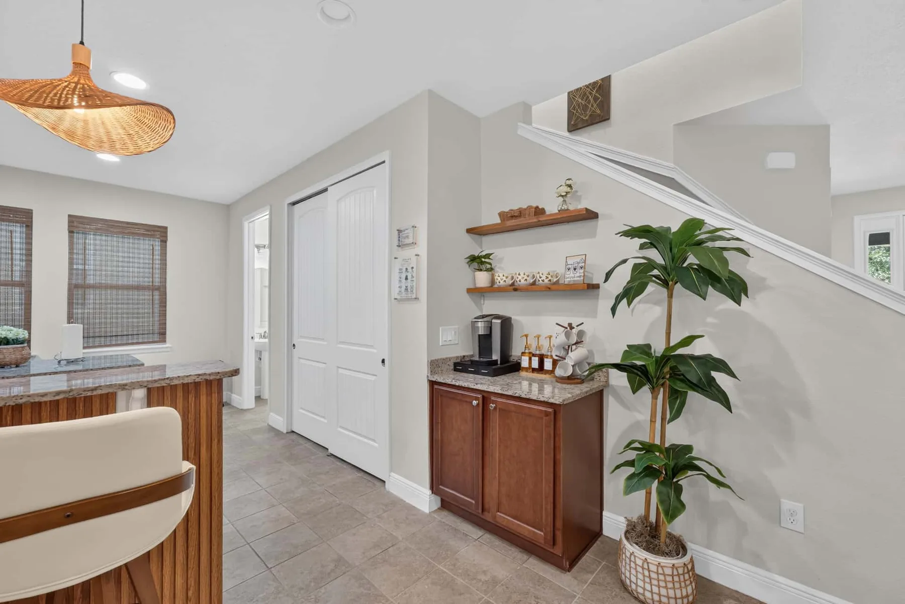 A bright kitchen area with a counter, cabinets, and a staircase.