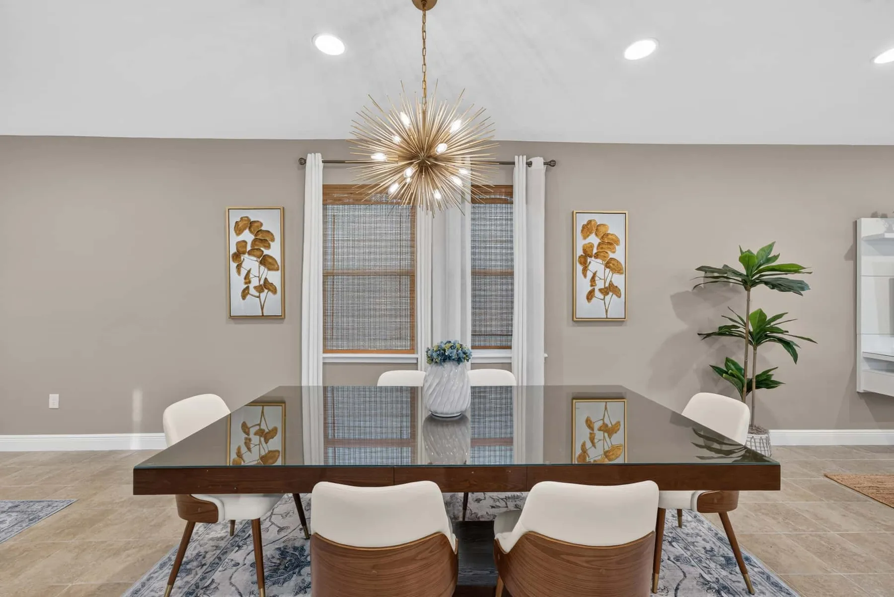 A dining area features a rectangular table, cushioned seating, and a hanging light.