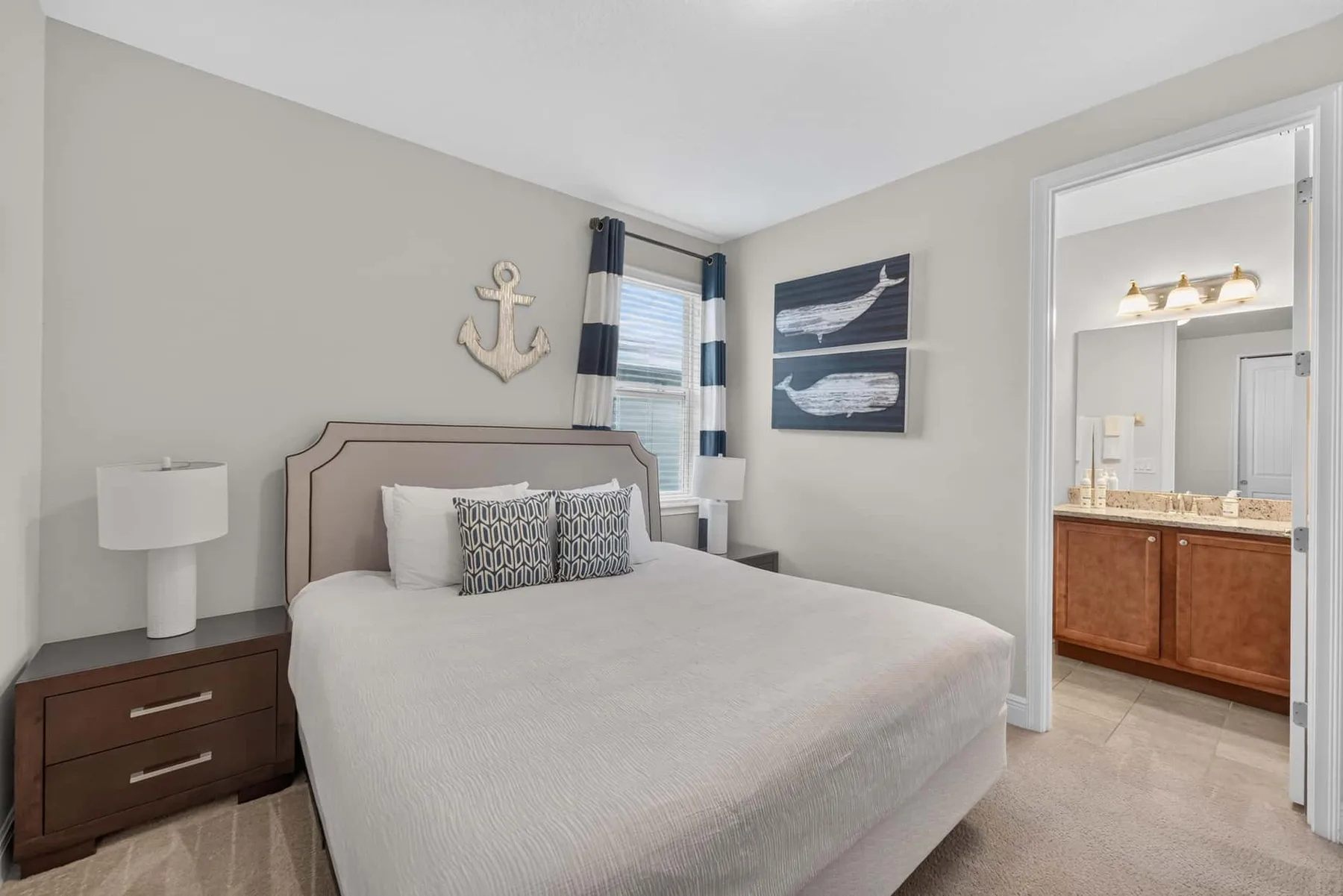 A bedroom with a neatly made bed and an adjoining bathroom visible through the doorway.