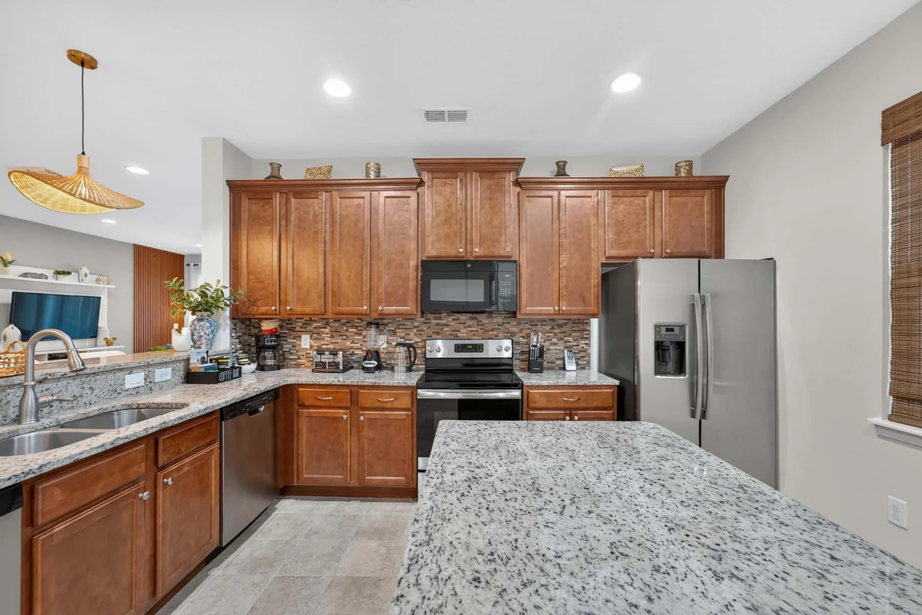 A kitchen with wooden cabinets, stainless steel appliances, and a large stone island.