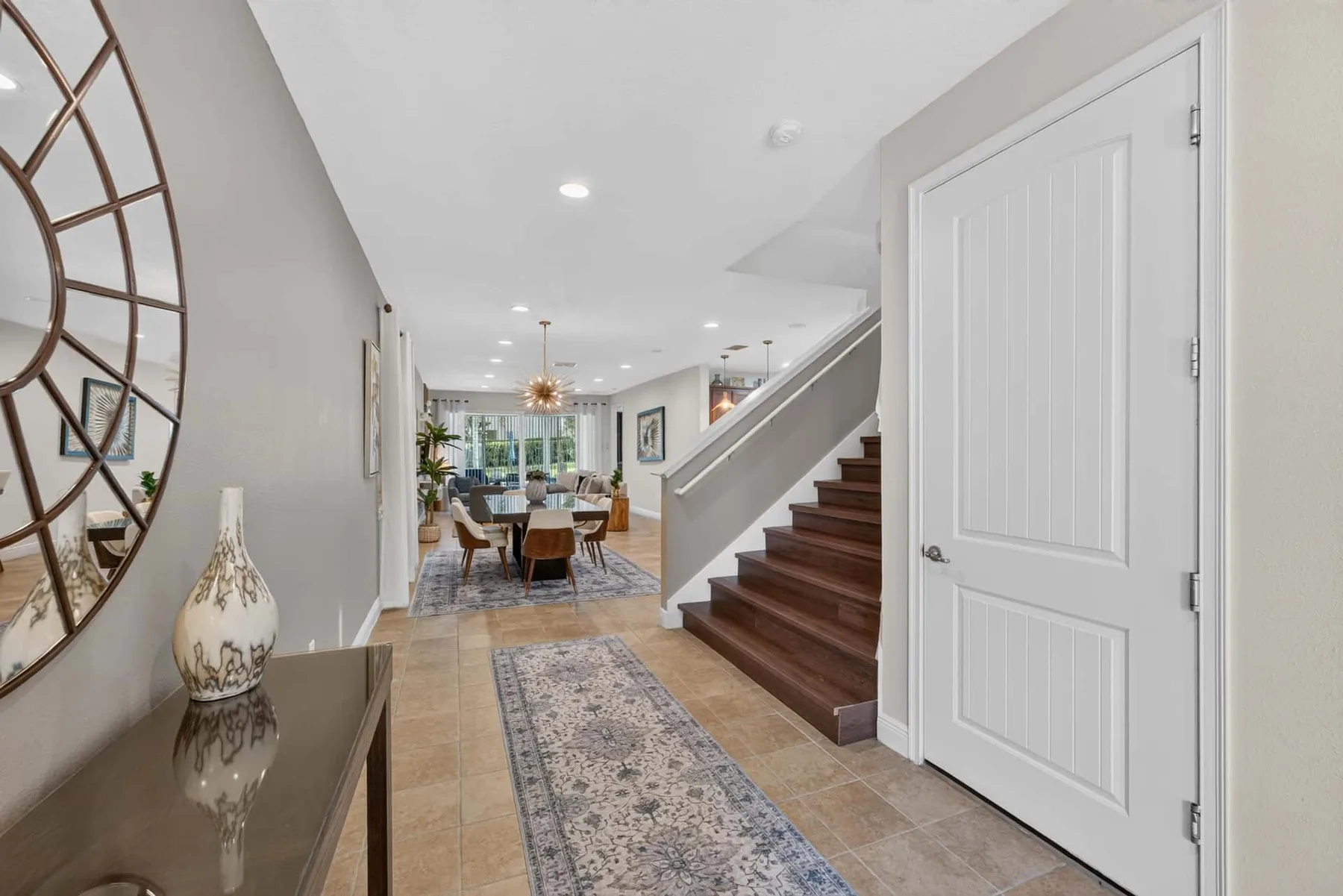 A bright entryway opens toward a dining area, with a staircase along the side.